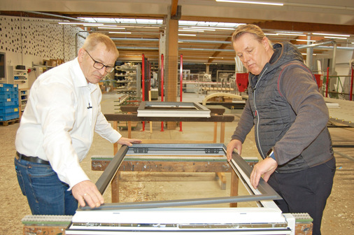 Hubert Hilbring (li.), Produktmanagement und Programmierung, sowie Jürgen Venhaus clipsen den Aluminiumrahmen auf das moderne Kunststofffenster. - © Kober