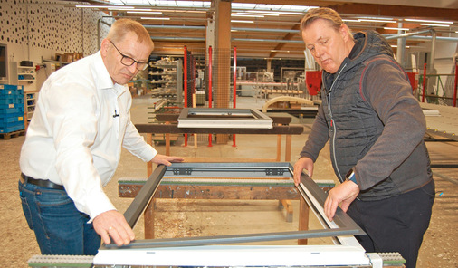 Hubert Hilbring (li.), Produktmanagement und Programmierung, sowie Jürgen Venhaus clipsen den Aluminiumrahmen auf das moderne Kunststofffenster. - © Foto: Kober